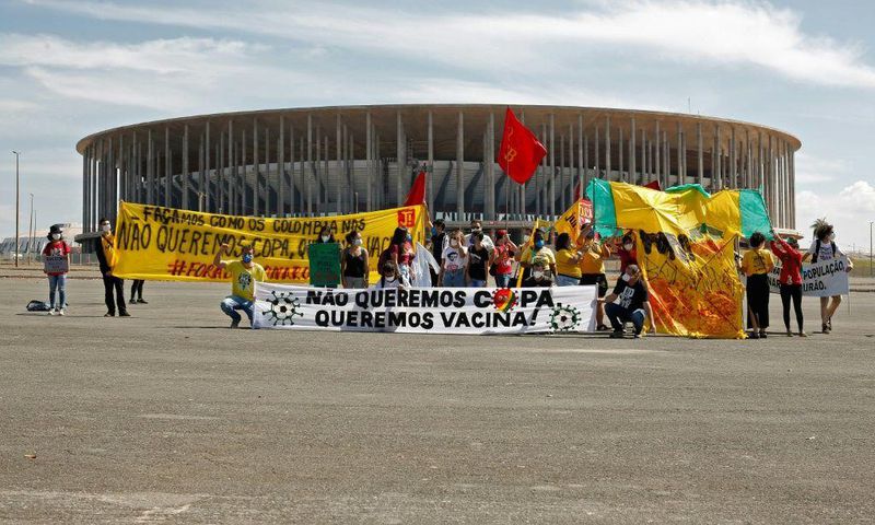 Demonstrators stand behind a banner reading 'We don't want the Copa, we want  vaccines' outside the Mane Garrincha stadium before the Copa America opening game