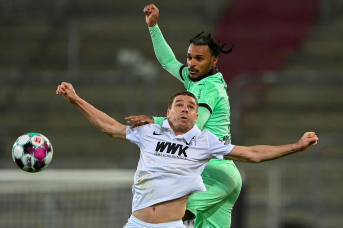 Arms race: Augsburg defender Raphael Framberger (left) challenges Moenchengladbach midfielder Valentino Lazaro