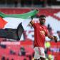 Manchester United midfielder Paul Pogba (L) and Amad Diallo (R) walk around the pitch with a Palestine flag