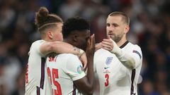 England's football team has united against raciism, Here midfielder Bukayo Saka (c) is consoled after failing to score in the penalty shootout of the Eur2020 final which England lost against Italy on Sunday
