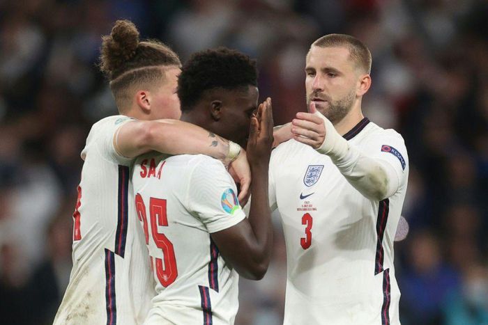 England's football team has united against raciism, Here midfielder Bukayo Saka (c) is consoled after failing to score in the penalty shootout of the Eur2020 final which England lost against Italy on Sunday