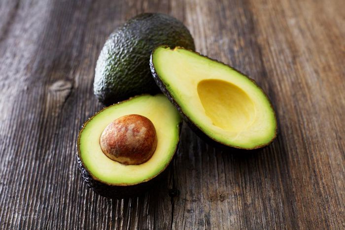 Whole and sliced avocado on wood