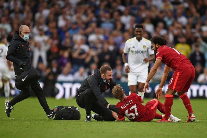 A trainer runs on the pitch to help Liverpool's Harvey Elliott (C)
