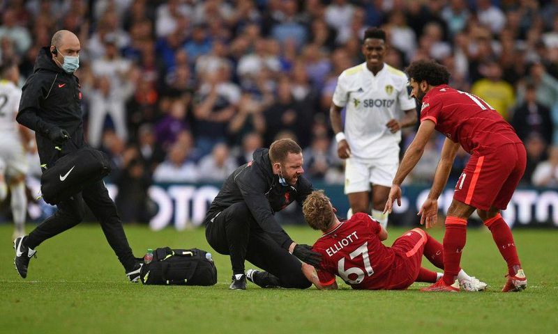 A trainer runs on the pitch to help Liverpool's Harvey Elliott (C)