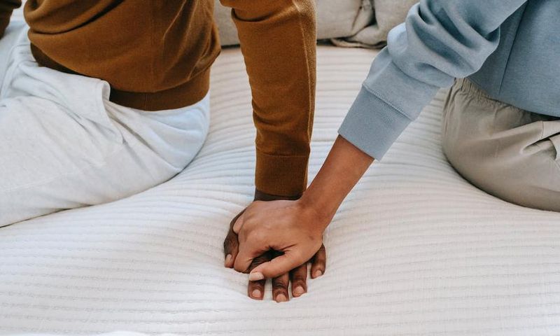 Couple holding hands on bed [Image: Alex Green]