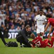 A trainer runs on the pitch to help Liverpool's Harvey Elliott (C)