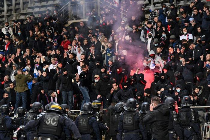 French anti-riot police officers arrive as supporters light a flare at half-time during the French Cup  match between Paris FC and Lyon