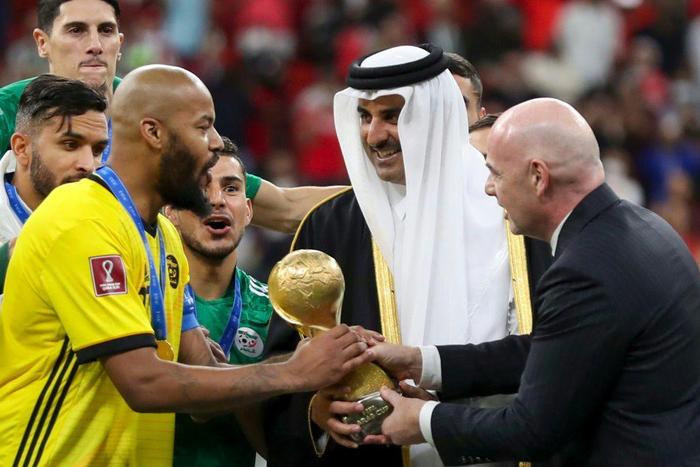 Qatar's Emir Sheikh Tamim bin Hamad al-Thani (C) and FIFA President Gianni Infantino (R) present Algeria's goalkeeper and captain Rais M'Bolhi with the the Arab Cup