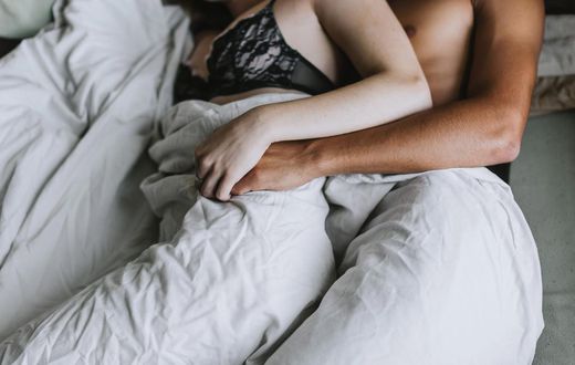 Cropped view of couple spooning in bed