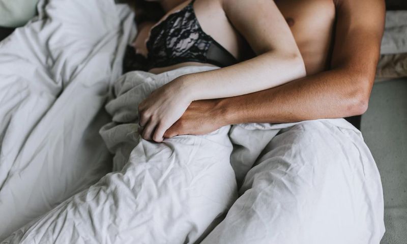 Cropped view of couple spooning in bed