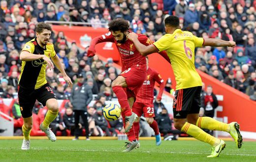 Liverpool star Mohamed Salah (C) shoots as two Watford defenders close in during a Premier League  match at the weekend