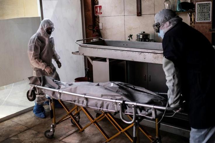 Mortuary workers move the body of a COVID-19 victim at a crematorium in Cuautitlan Izcalli, Mexico State