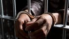A prisoner behind bars with hands cuffed.Caspar Benson/Getty Images