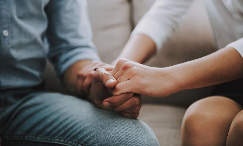 Close up. Man and woman hold hands tightly.