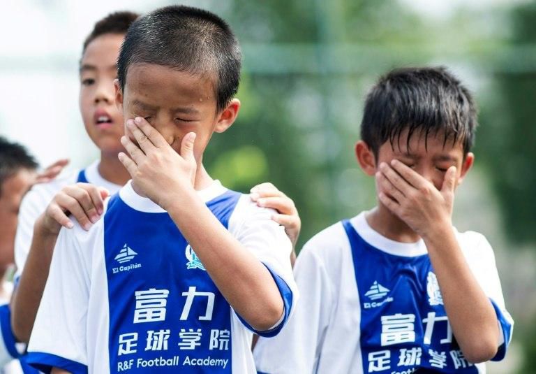 Boys wipe away perspiration during a training session at the Guangzhou R&F Football Academy in Meizhou