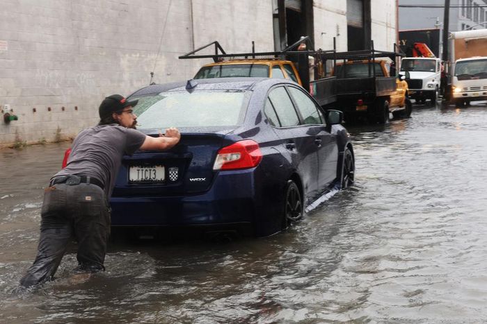 A man pushes a car through the flooded streets of Red Hook in Brooklyn on September 29, 2023.Spencer Platt/Getty Images