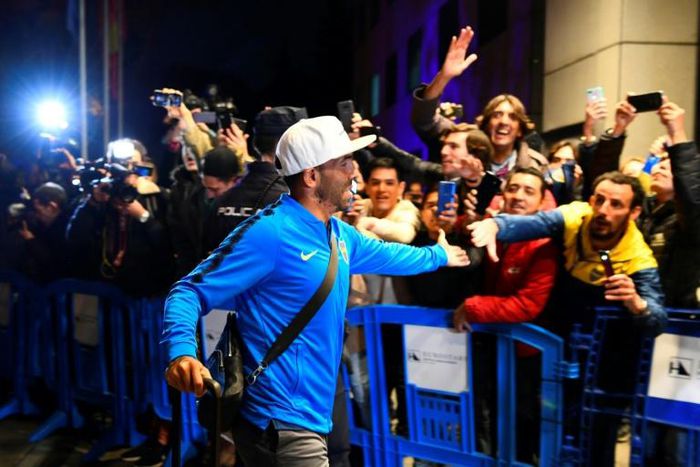 Carlos Tevez greets Boca Juniors supporters as his team arrive in Madrid for the delayed second leg of the Copa Libertadores final