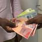 An image of person handing over Ghana cedi notes to another depicting a bribe