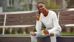 A young man using his phone while sitting on a park bench [Image: Gustavo Fring]