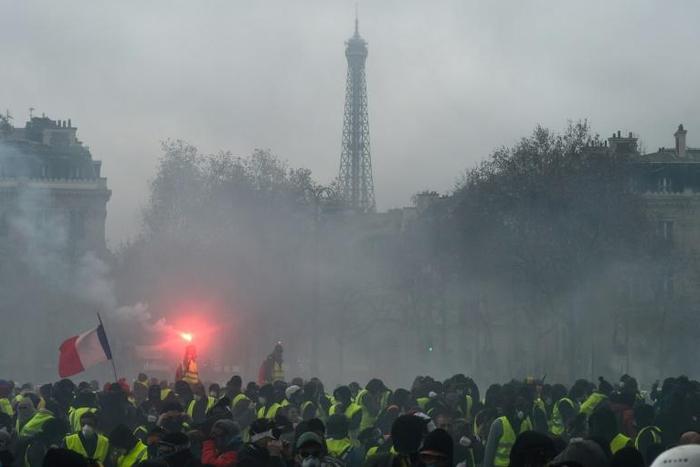 Demonstrators gather as tear gas fills the air at a "yellow vest" protest near the Eiffel Tower Saturday. The question now is whether the government's new measures will be enough to quell the anger.