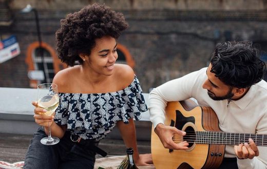 Man holding an acoustic guitar beside a woman [Photo: Viktoria Slowikowska]