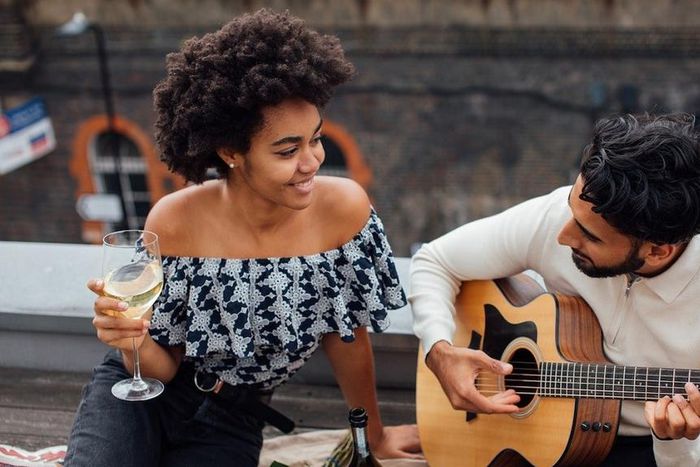 Man holding an acoustic guitar beside a woman [Photo: Viktoria Slowikowska]