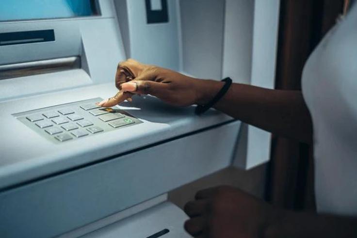 Black woman at an ATM [Shutterstock]