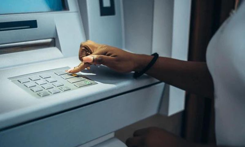 Black woman at an ATM [Shutterstock]