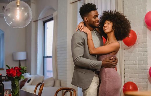 Couple dancing while hugging in a room near the table