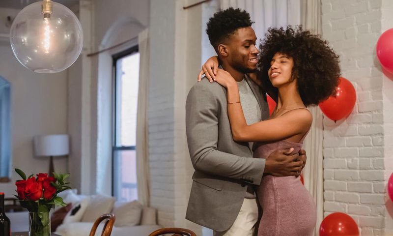 Couple dancing while hugging in a room near the table