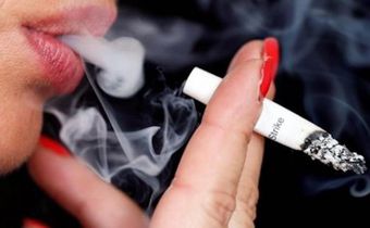 Smoke rises from a burning cigarette as a woman smokes on the street in Bordeaux