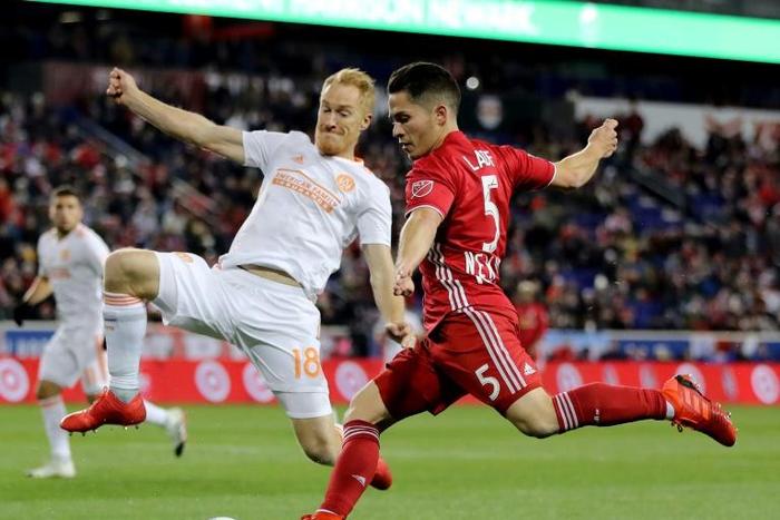 Connor Lade (R) of New York Red Bulls takes a shot as Jeff Larentowicz of Atlanta United defends in the first half during the Eastern Conference Finals Leg 2 match, at Red Bull Arena in Harrison, New Jersey, on November 29, 2018