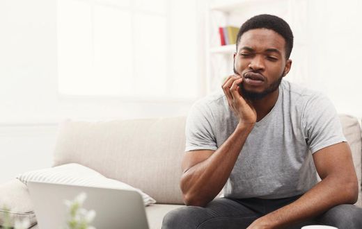 Young african-american man having toothache at home