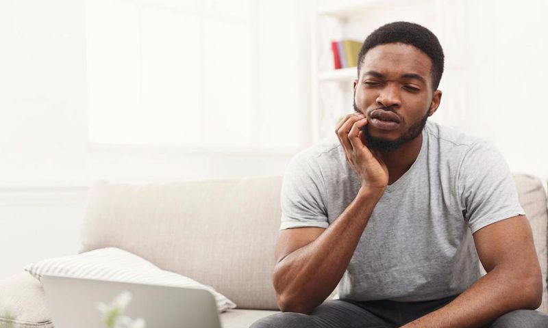 Young african-american man having toothache at home