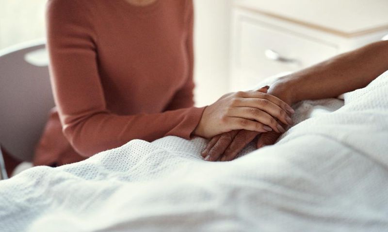 A woman holds a patients hand at a hospital.shapecharge/Getty Images