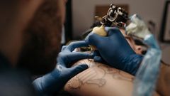 Tattoo artist tattooing a client's arm [Photo: Pavel Danilyuk]