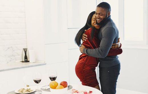 Man and woman hugging and Valentine dinner with wine on table [Image Credit: Gustavo Fring]