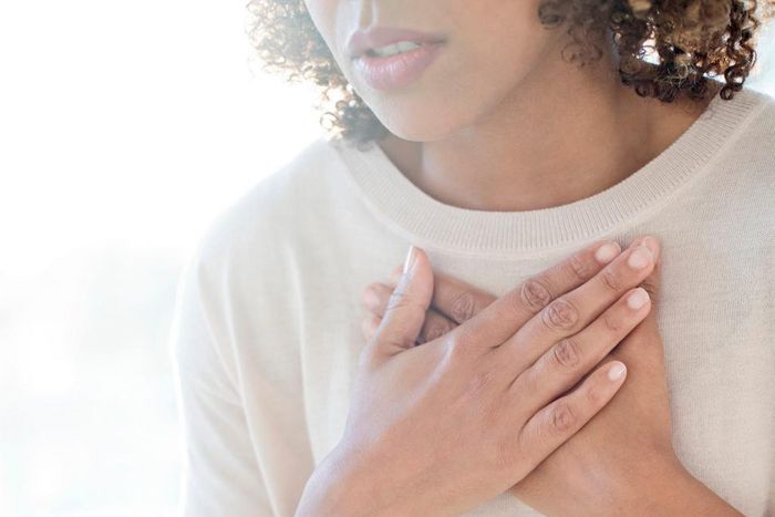 A stock image shows a woman clutching her chest.Science Photo Library/Getty Images
