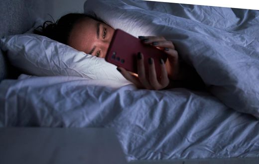 A woman lies in bed on her smartphone.Sergey Mironov/Getty Images