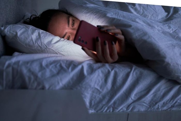 A woman lies in bed on her smartphone.Sergey Mironov/Getty Images