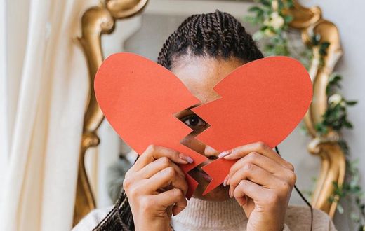 A woman holding a broken heart made of paper [Image: Antoni Shkraba]