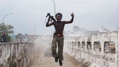 Joseph Duo, a Liberian militia commander loyal to the government, exults after firing a rocket-propelled grenade at rebel forces at a key strategic bridge July 20, 2003 in Monrovia, Liberia. Government forces succeeded in forcing back rebel forces in f...
