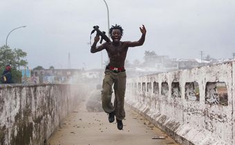 Joseph Duo, a Liberian militia commander loyal to the government, exults after firing a rocket-propelled grenade at rebel forces at a key strategic bridge July 20, 2003 in Monrovia, Liberia. Government forces succeeded in forcing back rebel forces in f...