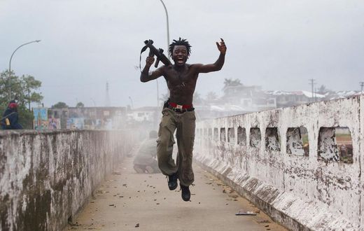 Joseph Duo, a Liberian militia commander loyal to the government, exults after firing a rocket-propelled grenade at rebel forces at a key strategic bridge July 20, 2003 in Monrovia, Liberia. Government forces succeeded in forcing back rebel forces in f...