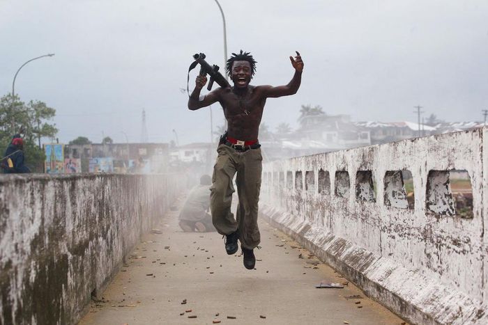 Joseph Duo, a Liberian militia commander loyal to the government, exults after firing a rocket-propelled grenade at rebel forces at a key strategic bridge July 20, 2003 in Monrovia, Liberia. Government forces succeeded in forcing back rebel forces in f...