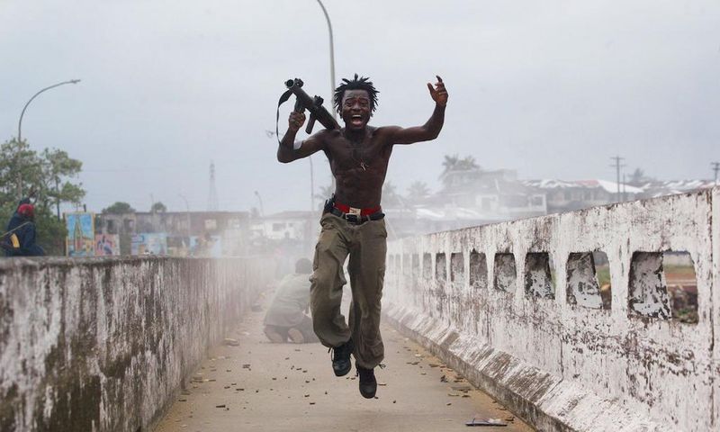 Joseph Duo, a Liberian militia commander loyal to the government, exults after firing a rocket-propelled grenade at rebel forces at a key strategic bridge July 20, 2003 in Monrovia, Liberia. Government forces succeeded in forcing back rebel forces in f...
