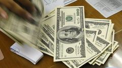 A money changer holds stacks of US dollar notes in JakartaThomson Reuters