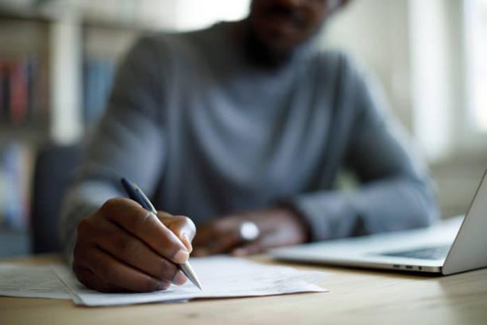 A Black person writing [iStock]