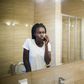 A Black woman looking in the mirror [Adobe Stock]