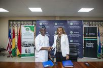 Olorunsola E Olowofeso, Director General of the West African Monetary Institute (WAMI), left, in a handshake with Carmelle Cadet, Founder and CEO of EMTECH, right, after the signing ceremony
